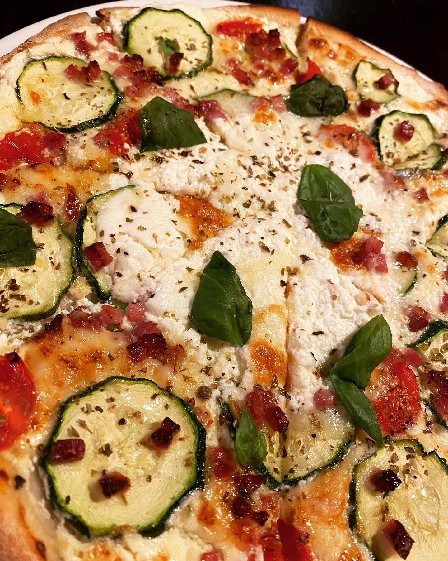 Frisch belegte Pizza mit Zucchini, Tomaten, Ricotta und Basilikum